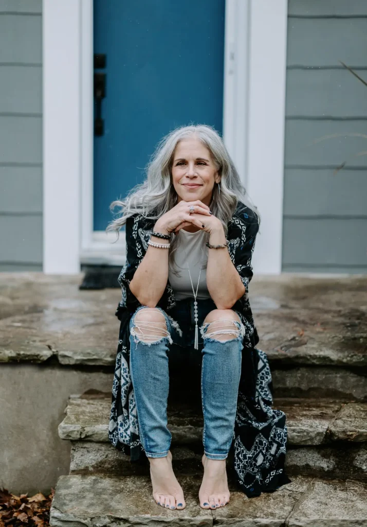 Dawne Sullivan, Holistic Nutritionist, Reiki Master, Cold Immersion Coach, Breathwork Facilitator sitting on porch outside in front of blue door