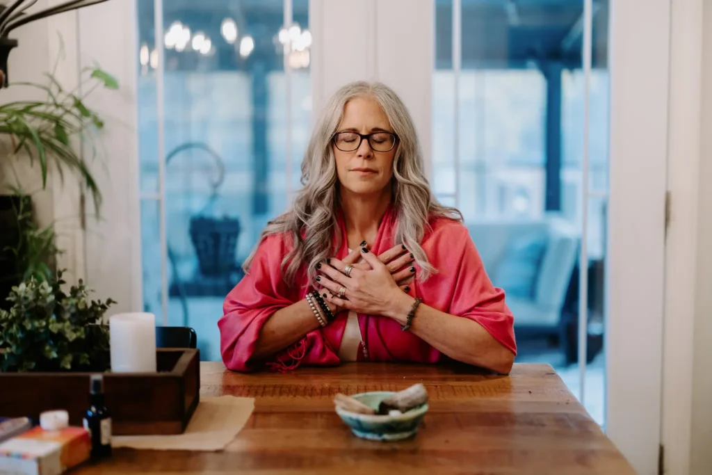 Dawne Sullivan, Holistic Nutritionist, Reiki Master, Cold Immersion Coach, Breathwork Facilitator sitting at table with eyes closed breathing deeply