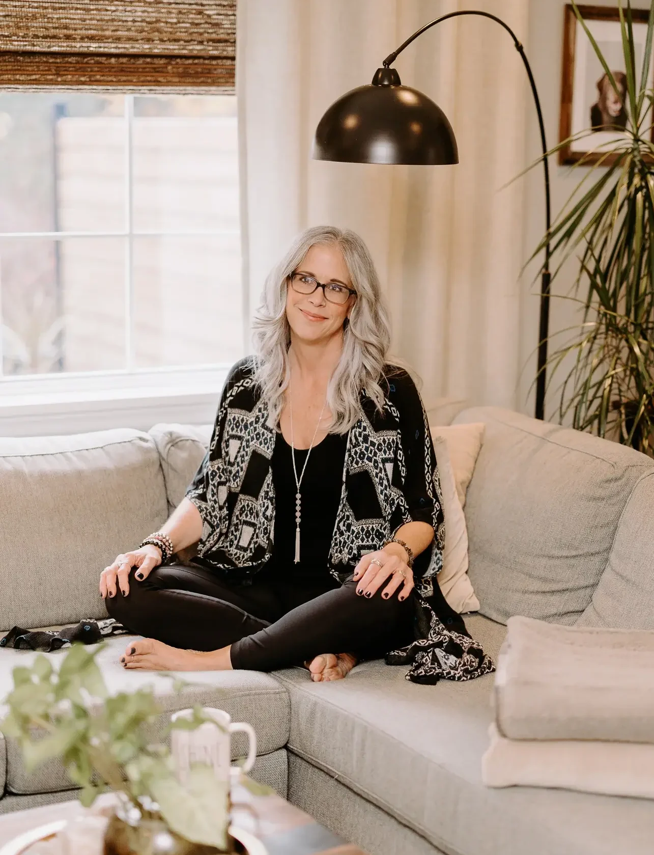 Dawne Sullivan, Holistic Nutritionist, Reiki Master, Cold Immersion Coach, Breathwork Facilitator sitting cross legged oh the couch